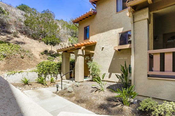Front view of a two-story house with stucco walls and a small porch entrance.