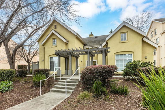 Front view of a two-story house with a gable roof and a pergola over the entrance.