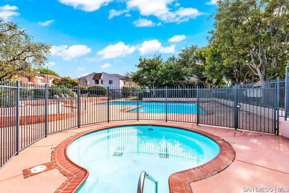 Outdoor swimming pool area with a round hot tub and surrounding fence.