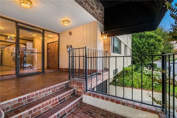 Front view of a building entrance with red brick steps and glass doors.