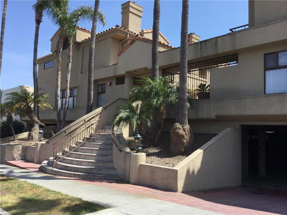 Front view of a multi-story building with stairs and palm trees.