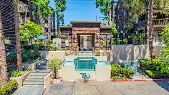 Front view of a multi-story residential building with a wood exterior and gated entrance.