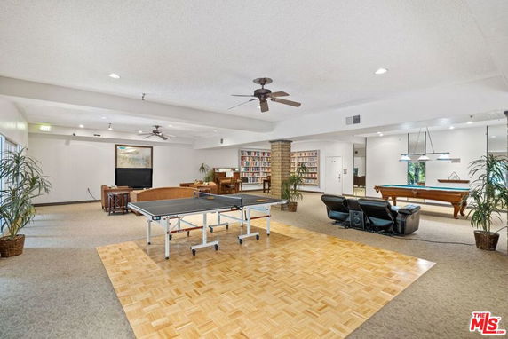Indoor space featuring a ping pong table, pool table, seating area, and bookshelves.