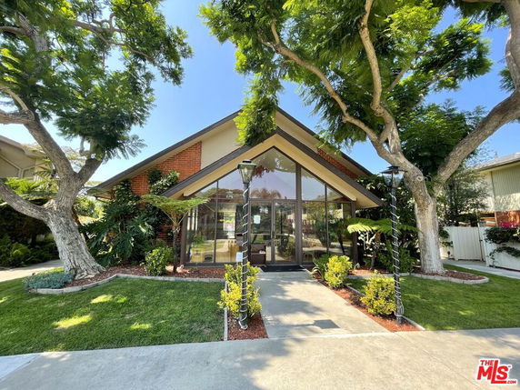 Front view of a house with large glass windows and a sloped roof.