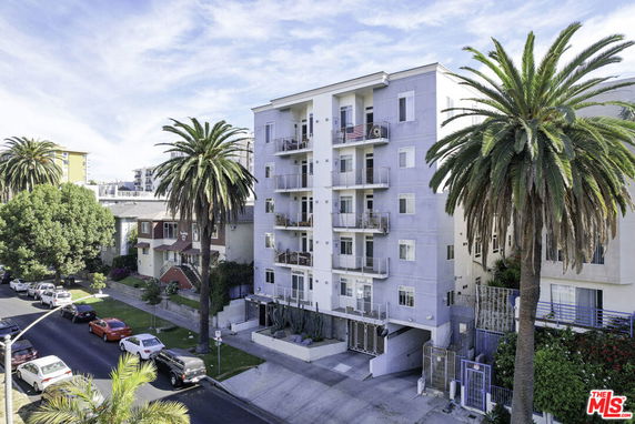 Front view of a multi-story residential building with balconies and a driveway.