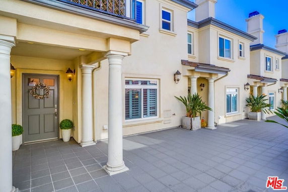 Front view of a multi-story townhouse with columns and plant decorations at the entrance.