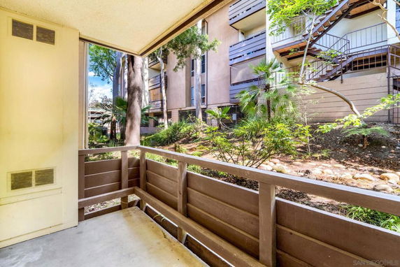 View from a balcony overlooking adjacent multi-story buildings and landscaped area.