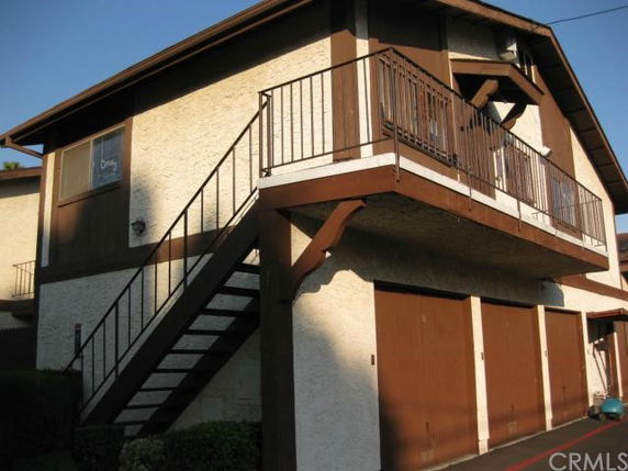 Front view of a two-story building with exterior staircase and multiple garage doors underneath.