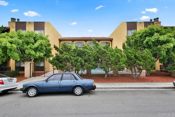Front view of a two-story building with arches and trees in front.