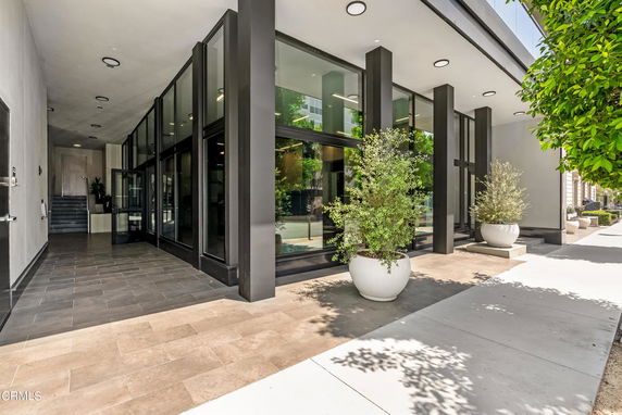 Front view of a modern building entrance with large glass windows and planters.