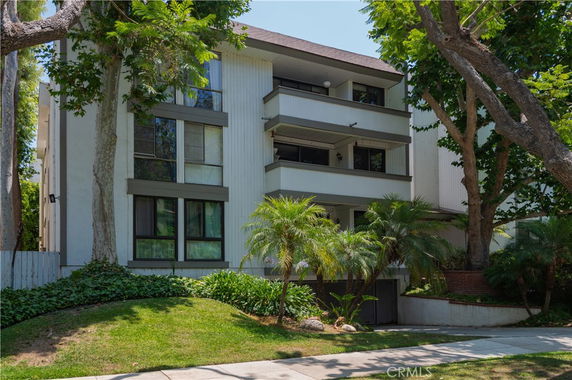 Front view of a multi-story apartment building with balconies and large windows.