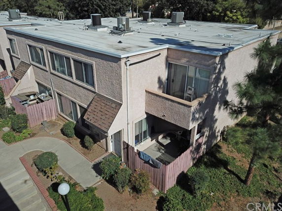 Aerial view of a two-story residential building with a flat roof and multiple air conditioning units on top.