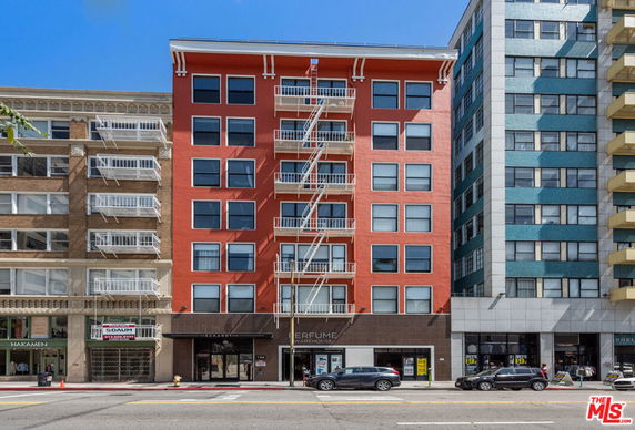Front view of a multi-story building with red exterior and fire escapes.
