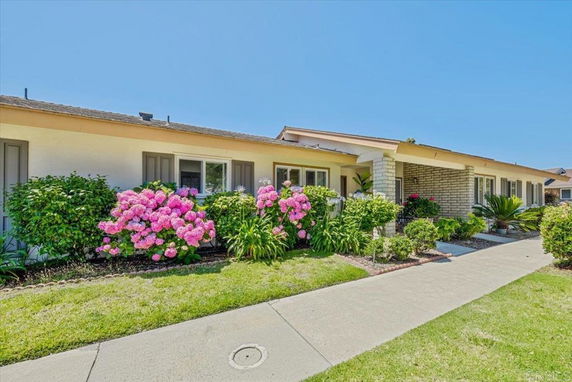Front view of a single-story house with a tiled roof and flower bushes.