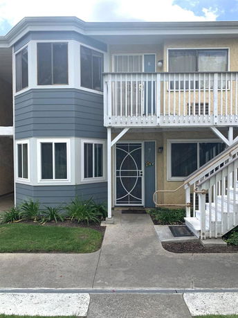 Front view of a two-story residential building with exterior stairway and balcony.