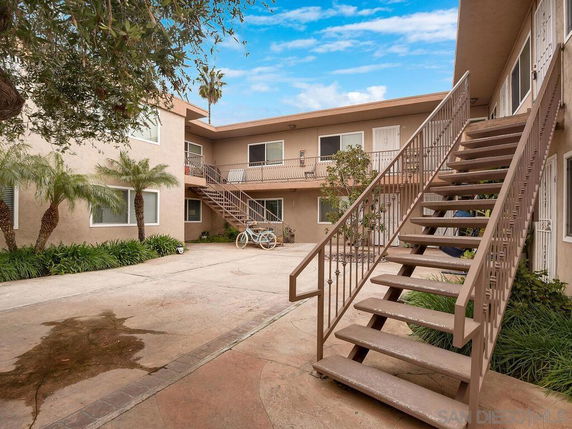 View of an apartment building courtyard with exterior staircases and a balcony.