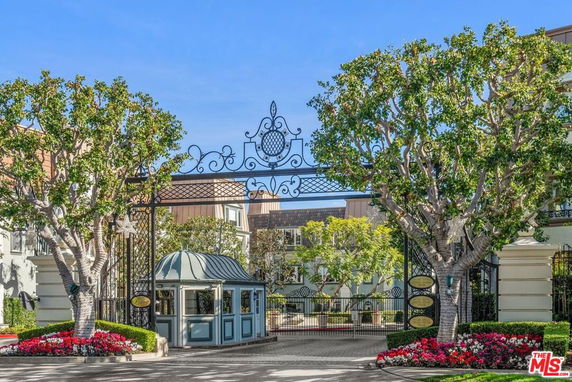 Front view of a decorative gated entrance to a residential building with trees on either side.