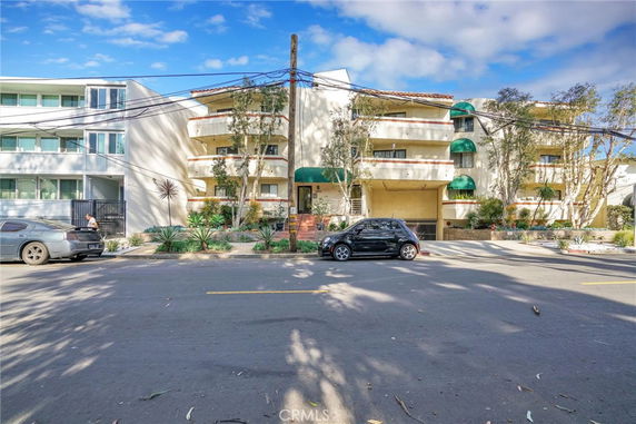 Front view of a multi-story apartment building with balconies and green awnings.