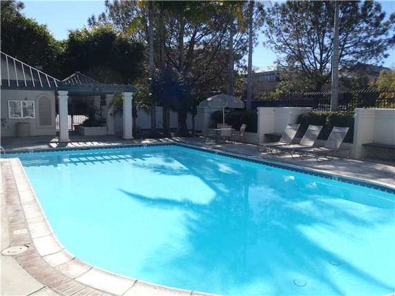 Outdoor swimming pool with lounge chairs and small structures nearby.