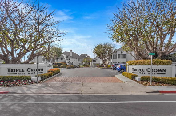 Entrance view of a residential complex with signs reading 'Triple Crown Del Mar'.