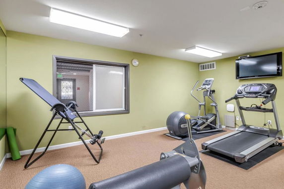 Indoor gym area with a treadmill, elliptical machine, and inversion table.