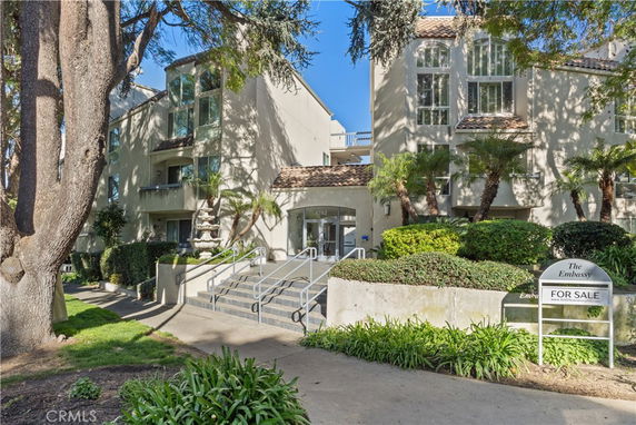 Front view of a multi-story residential building with a staircase leading to the entrance.
