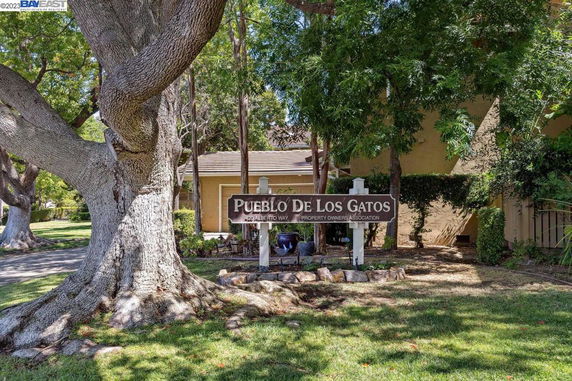 Front view of a residential building with a sign for Pueblo De Los Gatos.