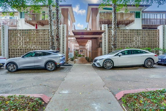 Outdoor parking area in front of a residential building with two parked cars.