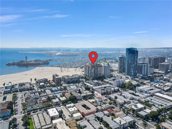 Panoramic view of a coastal urban area with a large building marked, beach, and ocean.