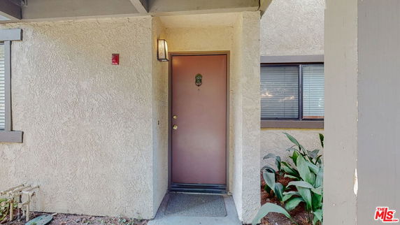 Front view of a building entrance with a brown door and adjacent windows.
