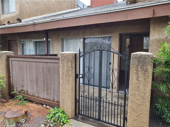Front view of a house with a metal gate and fenced entrance.