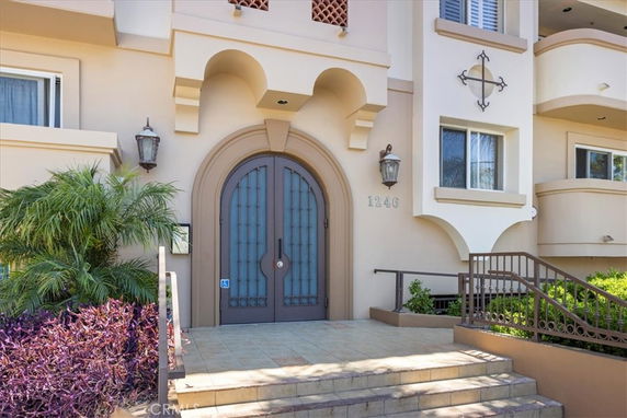 Front view of a building with an arched entrance and symmetrical windows.