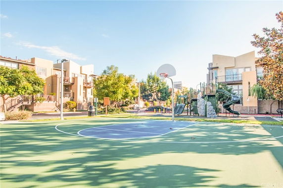 Outdoor play area with a basketball court and playground near residential buildings.