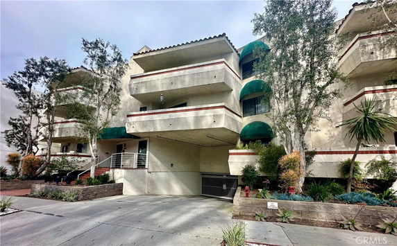 Front view of a multi-story building with balconies and greenery.