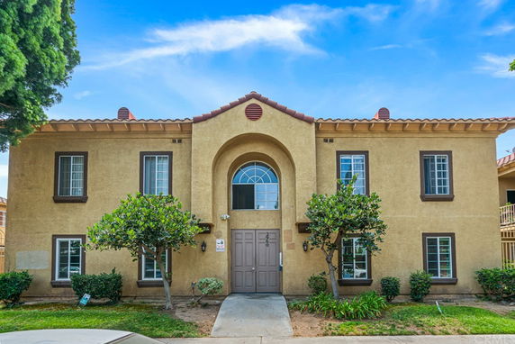 Front view of a two-story building with a central archway and decorative windows.