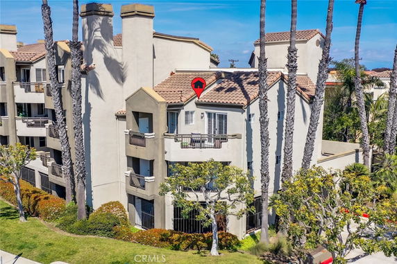 Front view of a multi-story residential building with balconies and a tiled roof.
