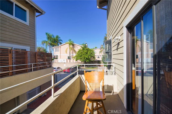 View from a balcony showing neighboring houses and a clear blue sky.