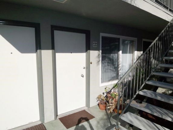 Exterior view of a building entrance with two white doors and stairs.