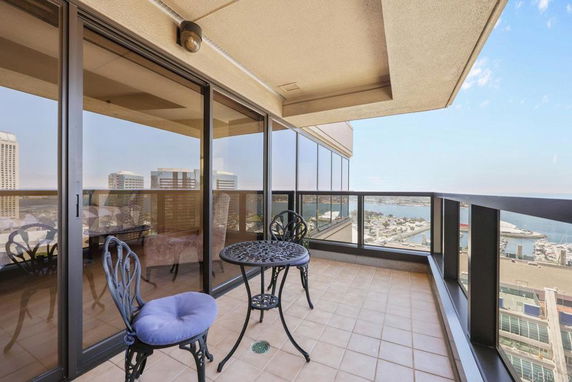 Balcony with glass railing offering a panoramic view of cityscape and waterfront.