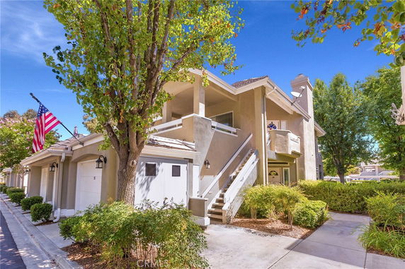 Front view of a two-story house with a staircase leading to the upper floor and a balcony.