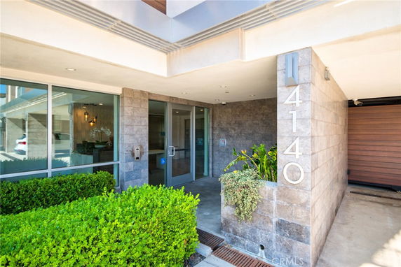 Front view of a building entrance with stone tiles and glass doors.