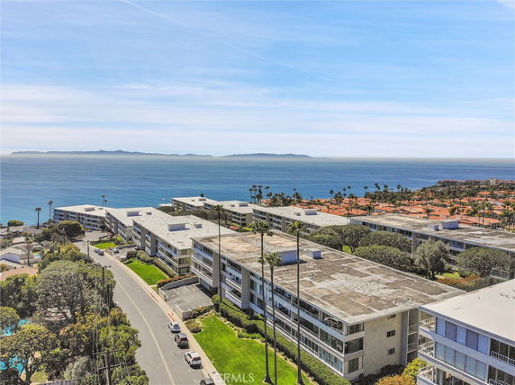 Aerial view of several multi-story buildings overlooking the ocean with distant islands visible on the horizon.