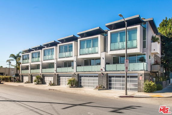 Front view of a modern multi-story residential building with large glass windows and balconies.