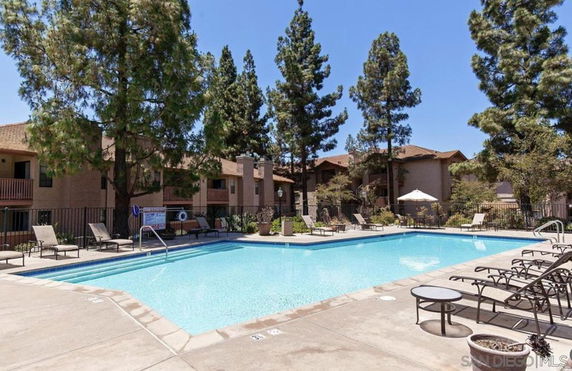 Outdoor swimming pool area with surrounding trees and lounge chairs.
