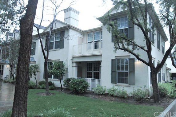 Front view of a two-story house with shutters and a small balcony.