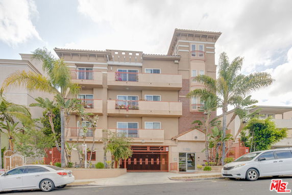 Front view of a multi-story apartment building with balconies and a secured entrance.