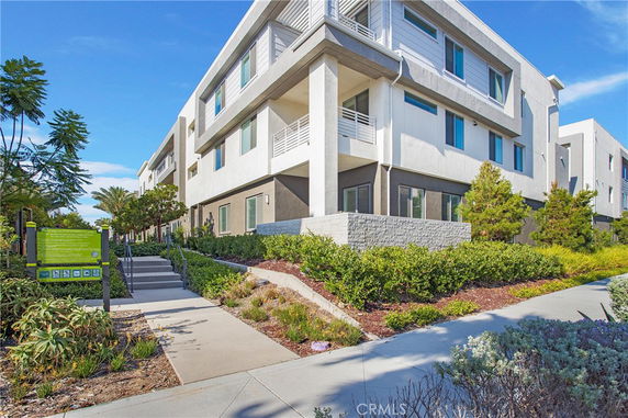 Front view of a modern multi-story building with balconies and large windows.