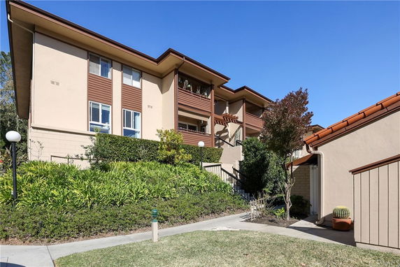 Front view of a multi-story building with a landscaped entrance and brown accents.