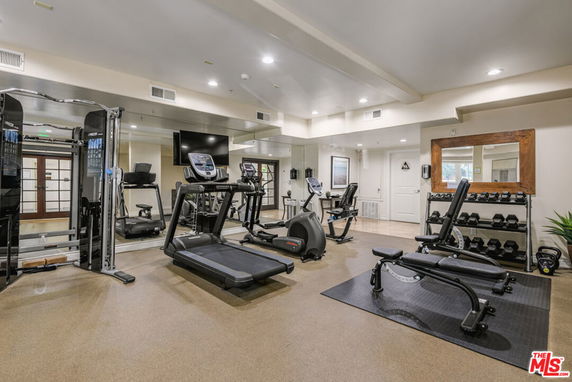Indoor gym area with exercise equipment and weights.