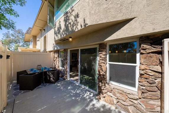 View of the exterior section of a building with stone accents and glass doors leading to a patio area.